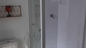 A bathroom with a glass-enclosed shower, a toilet, and a wall-mounted towel rack. - House two minutes from the beach (barfleur)