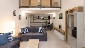 A modern living room with a sofa, coffee table, and a dining area in the background. - A bright and welcoming 50 square meters apartment, perfect for four people, located on the ground floor of the former headquarters of the Alinari Foundation, a completely renovated historic building.The property is located in the Santa Maria Novella area (Florence)
