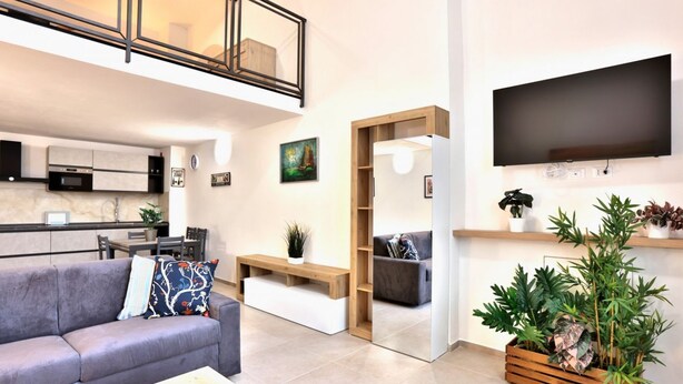 A modern living room with a sofa, coffee table, and a TV mounted on the wall. - A bright and welcoming 50 square meters apartment, perfect for four people, located on the ground floor of the former headquarters of the Alinari Foundation, a completely renovated historic building.The property is located in the Santa Maria Novella area (Florence)