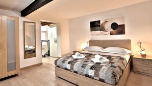 A modern bedroom with a large bed, wooden headboard, bedside tables, a mirror, and abstract wall art. - A bright and welcoming 50 square meters apartment, perfect for four people, located on the ground floor of the former headquarters of the Alinari Foundation, a completely renovated historic building.The property is located in the Santa Maria Novella area (Florence)