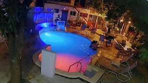 Ein kreisrunder Pool, umgeben von Liegestühlen und einer kleinen Terrassenfläche.