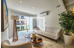 Ein modernes Wohnzimmer mit Sofa, Couchtisch, Lampe und einer Zimmerpflanze.