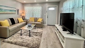 Un salon avec un canapé, une table basse et un téléviseur.