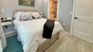 A bedroom with a bed, bedside table, and a nightstand. - Mangrove Nest (Fort Myers Beach)