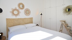 Quarto com cama, espelhos fixados na parede, abajur e escada.