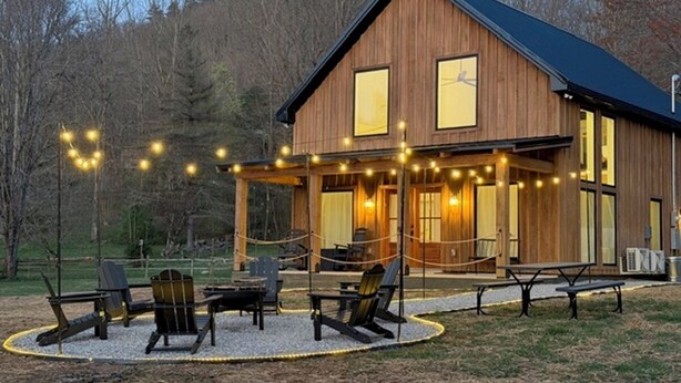 A wooden cabin with a porch, outdoor seating, and string lights. - Gorgeous 1BD+Loft Cabin w/ River Access + Fireplace (Townsend)