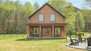 A wooden cabin with a porch, large windows, and outdoor seating. - Gorgeous 1BD+Loft Cabin w/ River Access + Fireplace (Townsend)