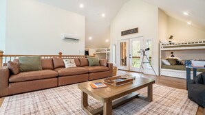 A spacious living area with a brown leather sofa, a wooden coffee table, and a balcony with a telescope. - Gorgeous 1BD+Loft Cabin w/ River Access + Fireplace (Townsend)