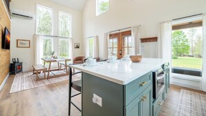 A spacious kitchen with a large island, wooden flooring, and a view of the outdoors. - Gorgeous 1BD+Loft Cabin w/ River Access + Fireplace (Townsend)
