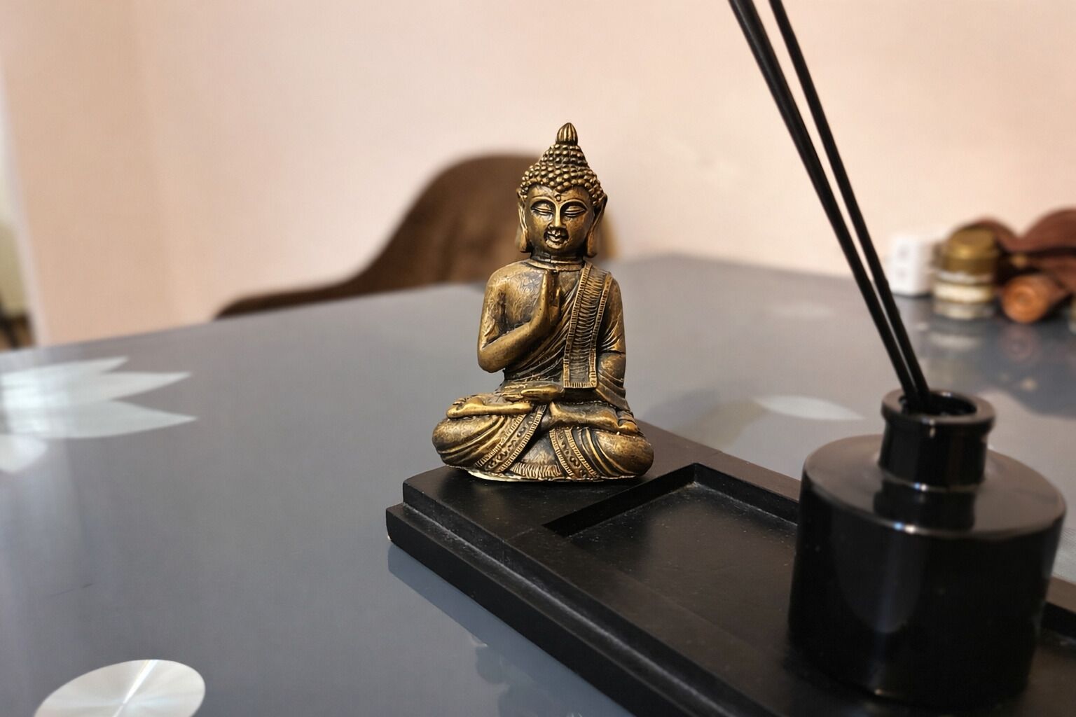A Buddha statue on a black table with a black candle holder beside it.