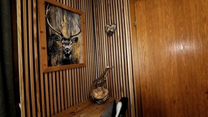 A wooden wall with vertical slats, a framed painting of a deer, a heart-shaped decoration, and a rustic vase. - Family room (1 double, 2 extra beds) (Zederhaus)