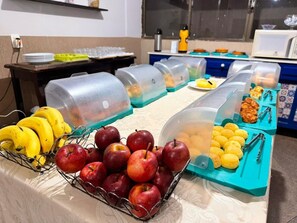 A buffet with fruits and food containers. - Império Hotel (Caçu)