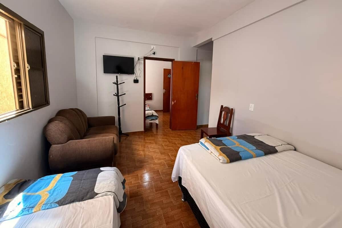 Una habitación con dos camas, un sofá, un televisor y una puerta de madera.