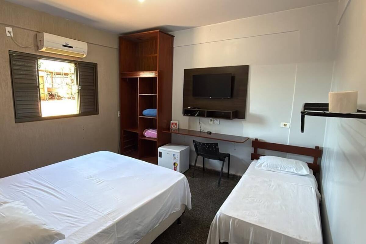 Una habitación con dos camas, un escritorio, un televisor y un armario.