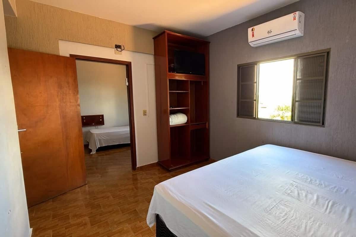 Un dormitorio con cama, armario, televisor y aire acondicionado.
