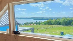 Une pièce dotée d’une grande fenêtre donnant sur un lac, d’une petite table et d’une prise de courant.