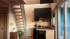 Een compacte keuken met houten wanden, een ingebouwde magnetron en een klein spoelgedeelte.