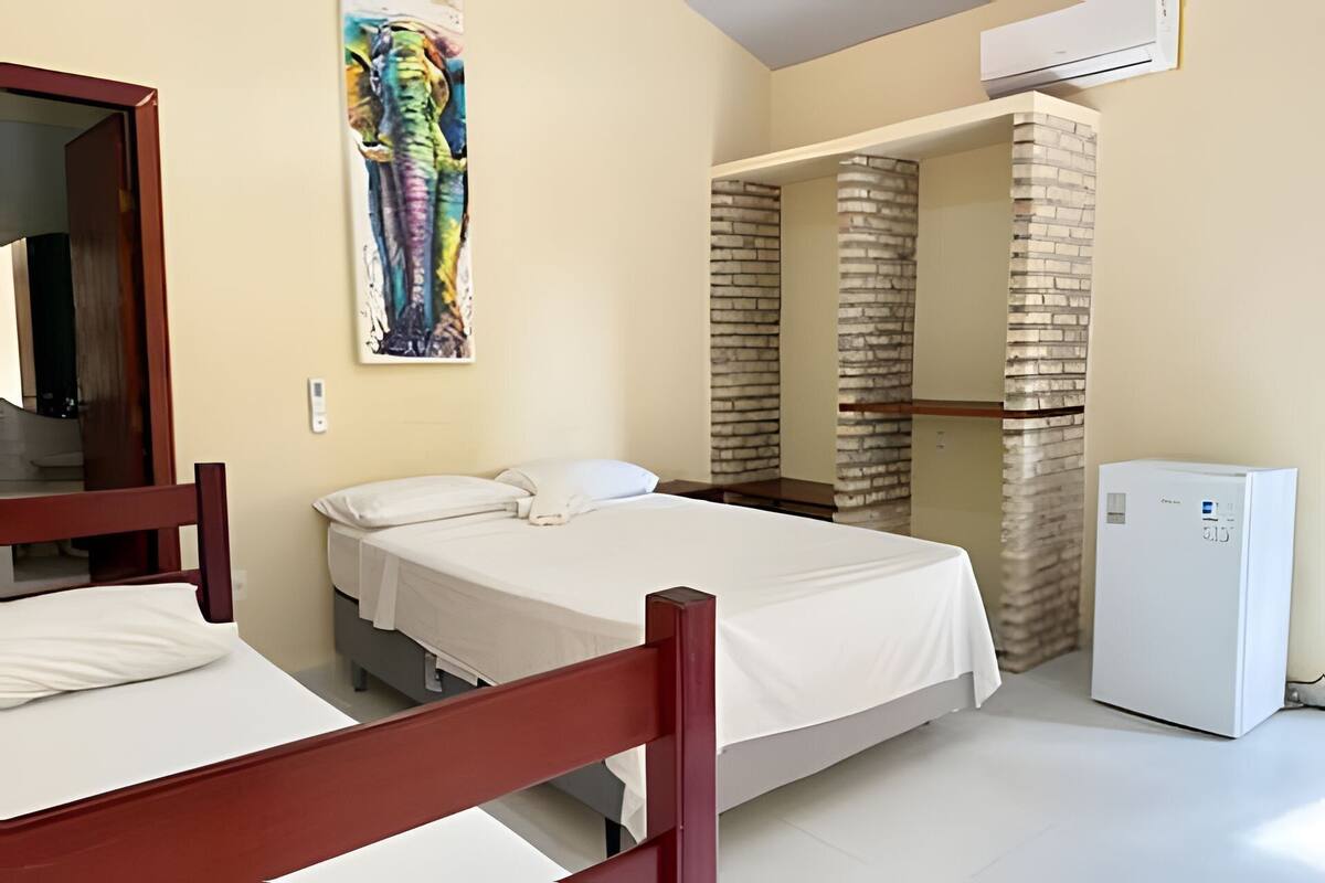 Ein Hotelzimmer mit einem Bett, einem kleinen Kühlschrank, einem Gemälde und einer Ziegelwand.