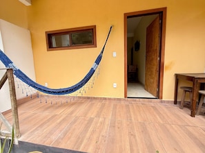 Een hangmat in een kamer met houten vloeren, een deur naar een andere ruimte en een kleine tafel.