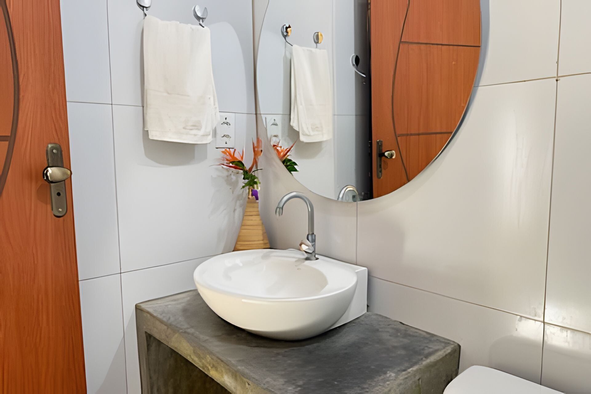 A bathroom with a round mirror, a white sink, and wooden doors.