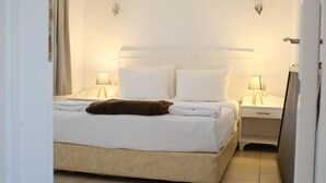 Una habitación de hotel con una cama, dos lámparas de noche, una mesita de noche y una puerta.