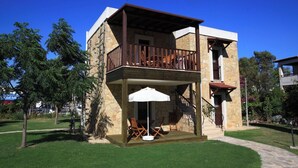 Un edificio de dos pisos con balcón, mobiliario exterior y fachada de piedra.
