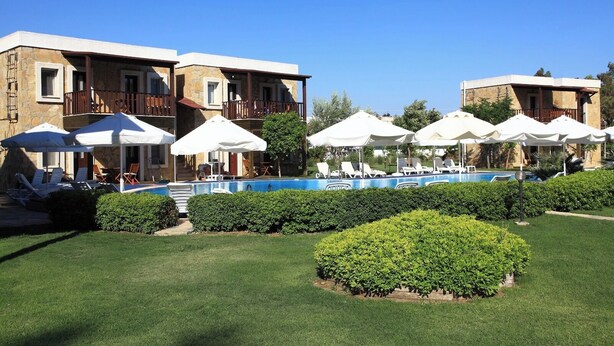Un hotel con piscina, mobiliario exterior y un jardín bien cuidado.