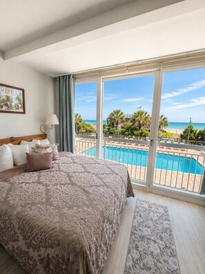 A hotel room with a large bed, a view of a swimming pool, and a balcony overlooking the beach. - Oceanfront Pool View Condo by Pier! Yachtsman S205 (Myrtle Beach)