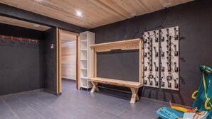 A room with a wooden ceiling, a black wall with a white shelf unit, a wooden bench, and a wall-mounted control panel. - Morzine chalet with hot tub. Ski and MTB friendly (Montriond)