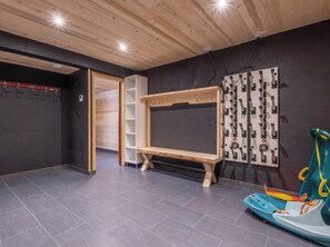 A room with a wooden ceiling, a black wall with a white shelf unit, a wooden bench, and a wall-mounted control panel. - Morzine chalet with hot tub. Ski and MTB friendly (Montriond)
