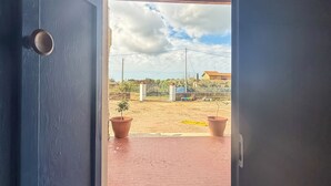An open doorway leading to a paved area with a wooden ceiling and potted plants. - Root and Rise (Caltagirone)