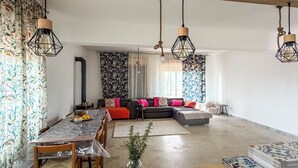 A spacious living area with a wooden ceiling, a dining table with chairs, a sofa set, and hanging pendant lights. - Root and Rise (Caltagirone)