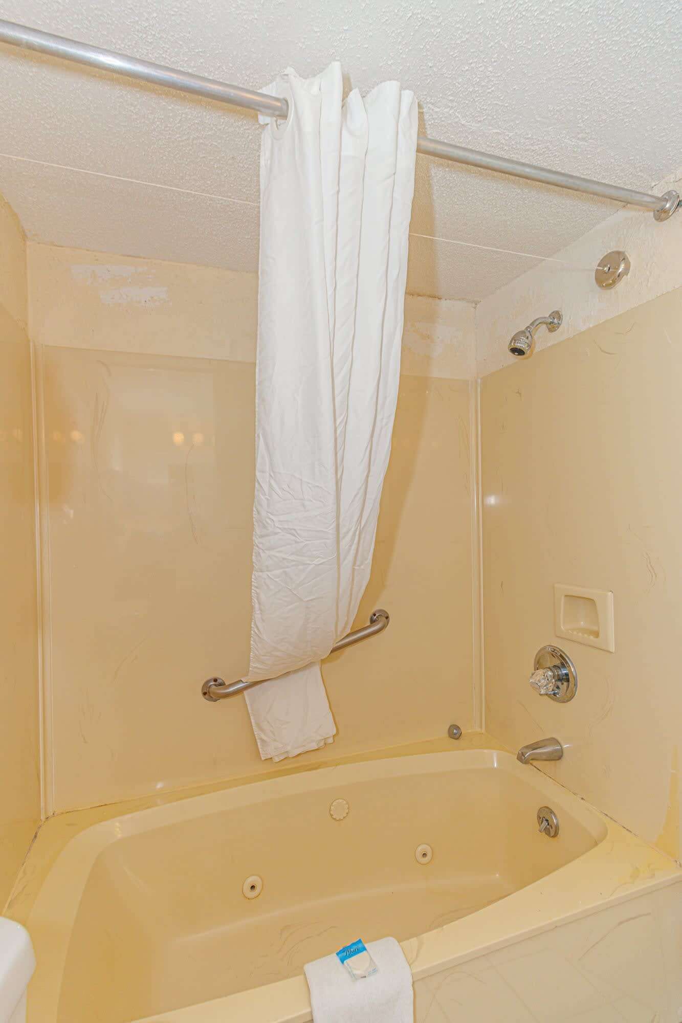 Ein Badezimmer mit einer Badewanne, einer Duschvorhang, einem Handtuchhalter und einer Duschbrause.