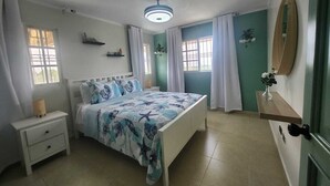 Un dormitorio con cama, mesita de noche, cómoda y ventilador de techo.