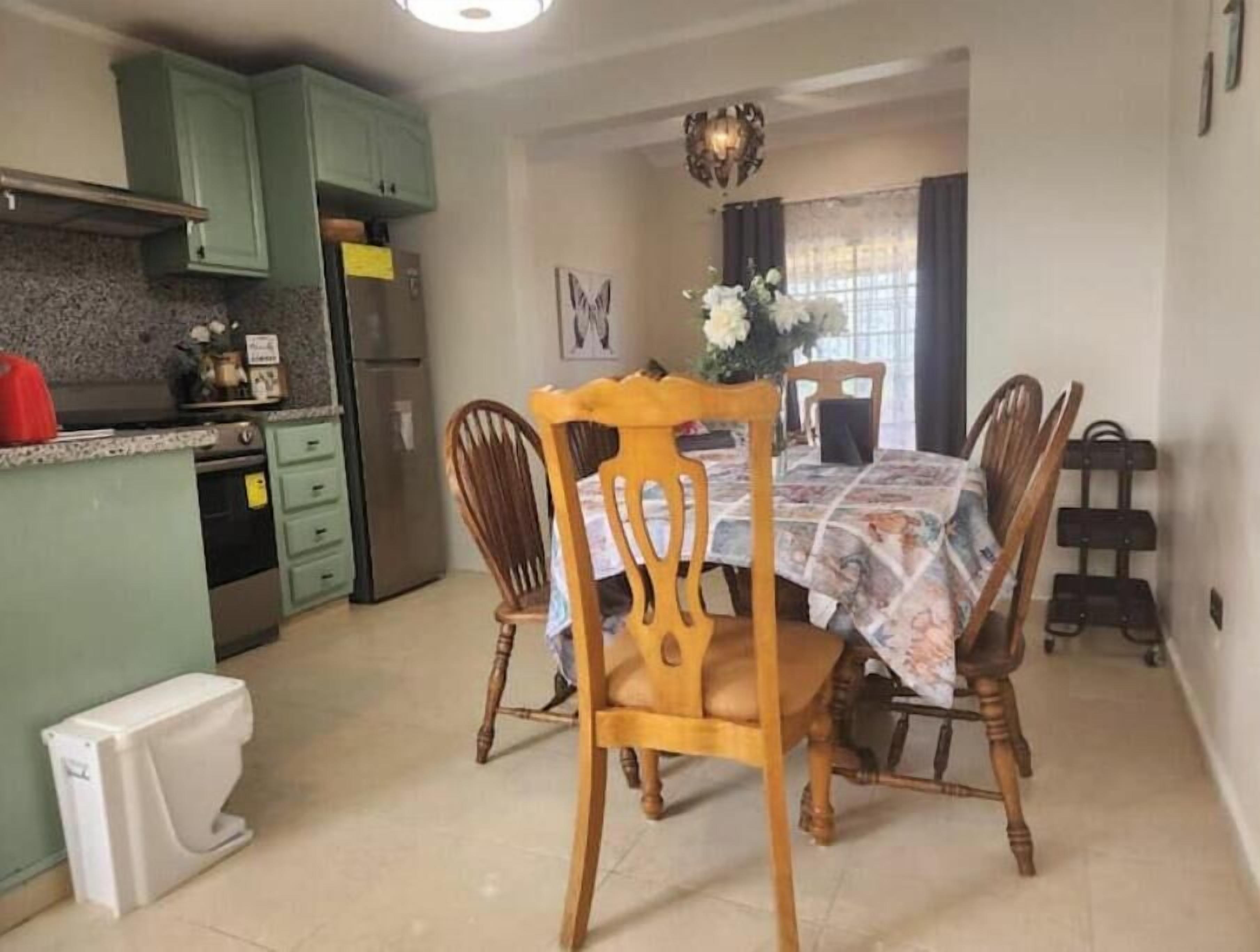 Una cucina compatta con zona pranzo, frigorifero, mobili e un water bianco.