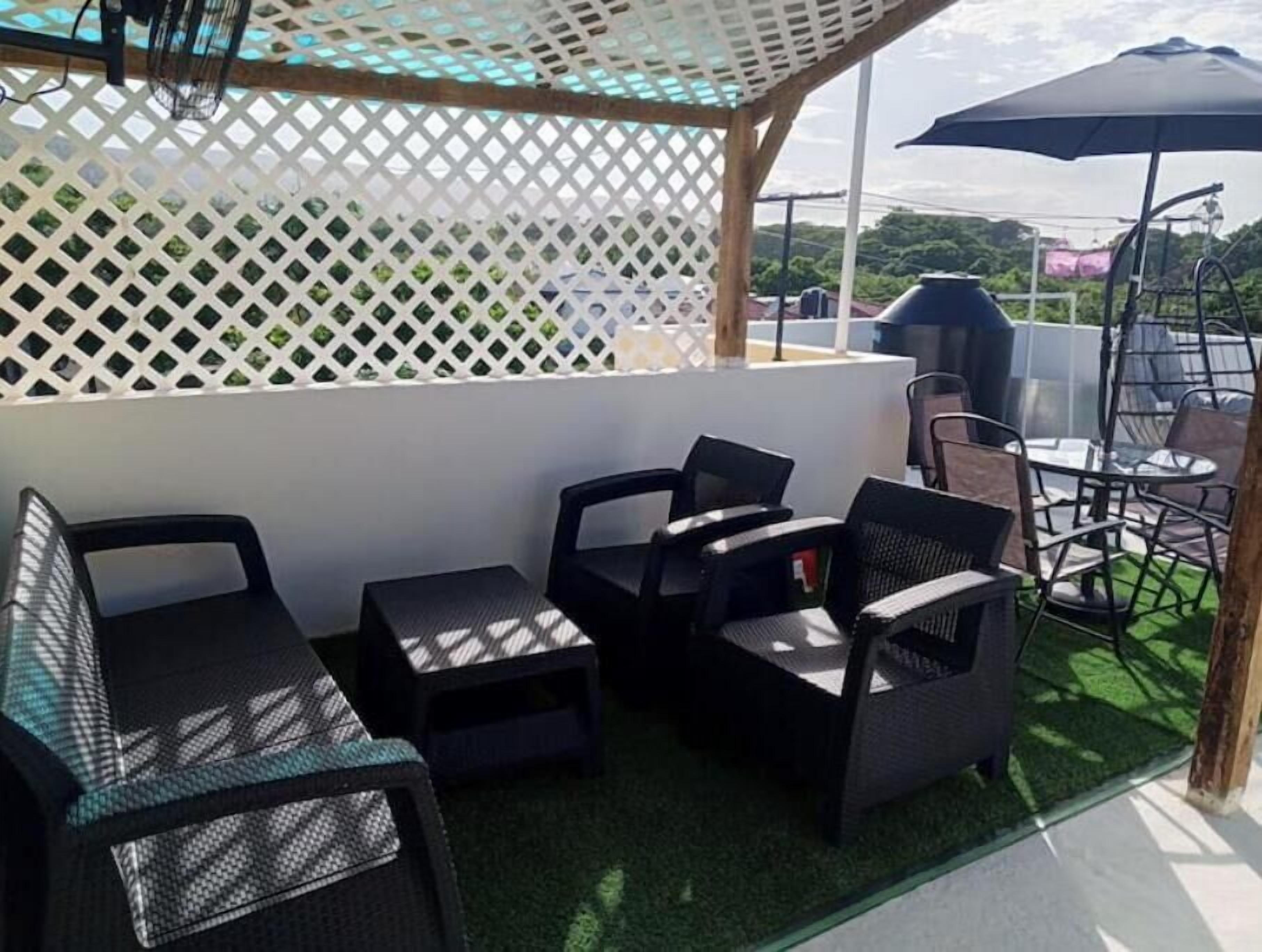An outdoor patio area with a white lattice partition, a grill, and outdoor furniture.