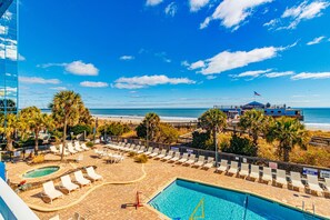 Zwembad van een resort met ligbedden, een zwembad en uitzicht op het strand en de oceaan.
