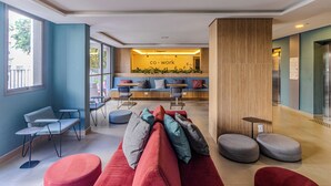 A modern lobby with seating areas, a reception desk, and a visible elevator. - Your Code Liberdade (São Paulo)