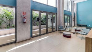 A modern lobby with glass doors, seating areas, and a fire extinguisher. - Your Code Liberdade (São Paulo)