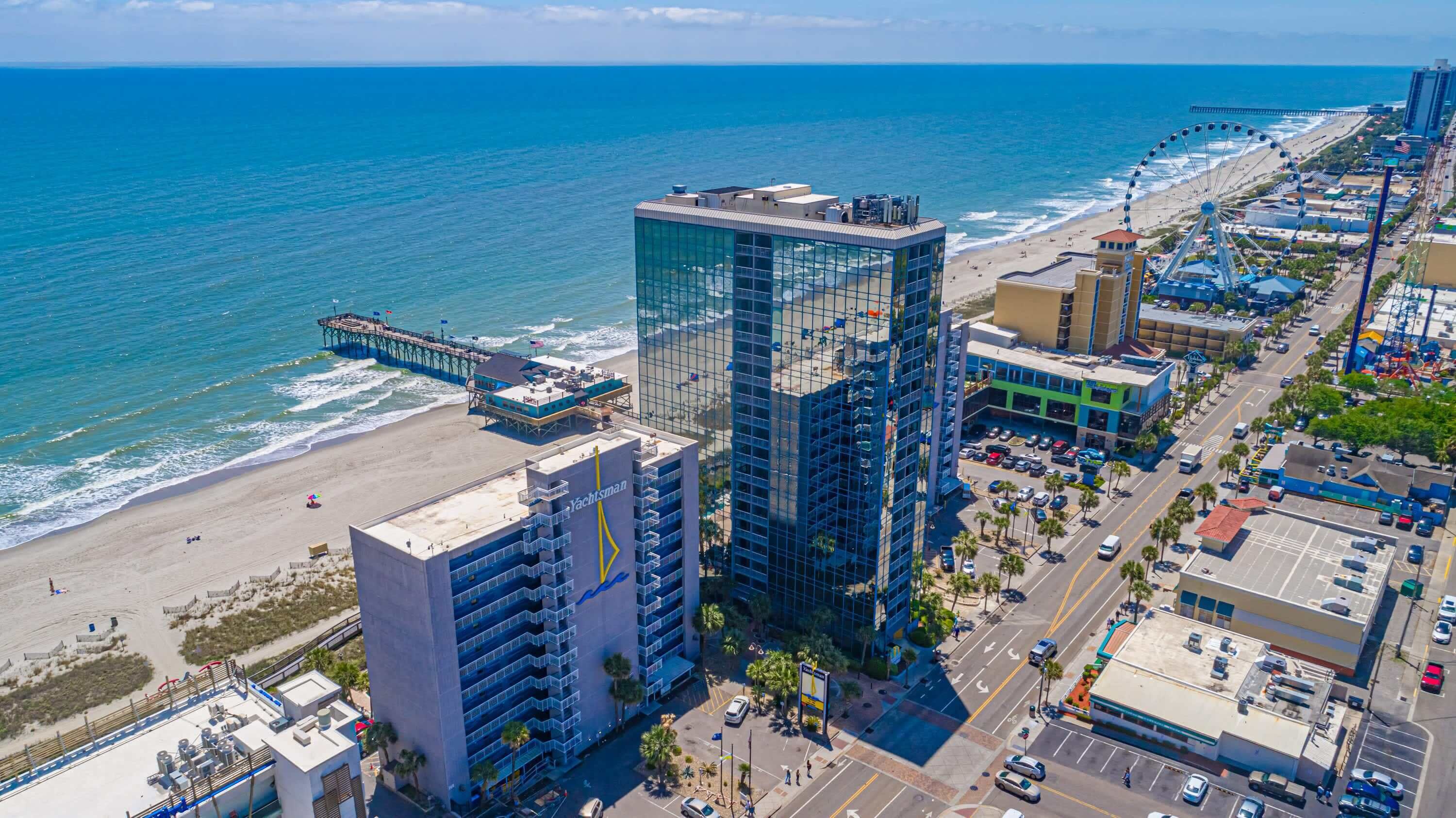 Un paisaje urbano costero con rascacielos, una playa y un muelle.