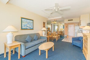 A hotel room with a sofa, a small table, a ceiling fan, a dining area with chairs, and a kitchen area. - Yachtsman S600 1 BR (Myrtle Beach)