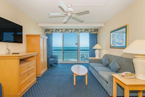 A hotel room with a balcony, a TV, a sofa, a table, and a ceiling fan. - Yachtsman S600 1 BR (Myrtle Beach)
