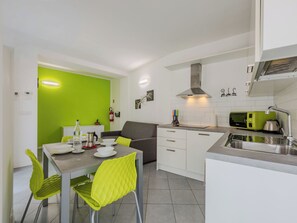 A modern kitchen with a dining area, green walls, and a grey sofa. - Antica Corte by Interhome (Arco)