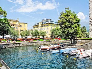 A waterfront area with boats docked, a stone wall, and buildings in the background. - Antica Corte by Interhome (Arco)