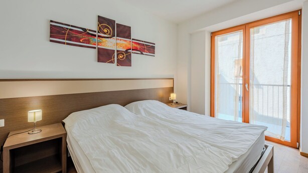 A hotel room with a bed, bedside tables, a wall-mounted artwork, and a large window with blinds. - Antica Corte by Interhome (Arco)