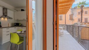 A modern kitchen with white cabinets and a dining area with a green chair. - Antica Corte by Interhome (Arco)