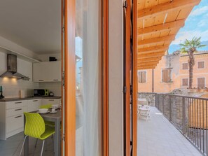 A modern kitchen with white cabinets and a dining area with a green chair. - Antica Corte by Interhome (Arco)