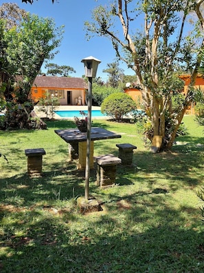 A garden with a pool, stone benches, and a lamp post.