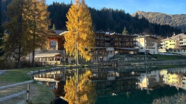 Un hotel sul lago con diversi edifici, un pontile e una foresta circostante.