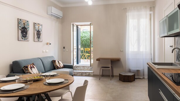 A modern kitchen with a dining area, a sofa, and artwork on the wall. - Casa Amarantia-Appartamento 2 (Noto)